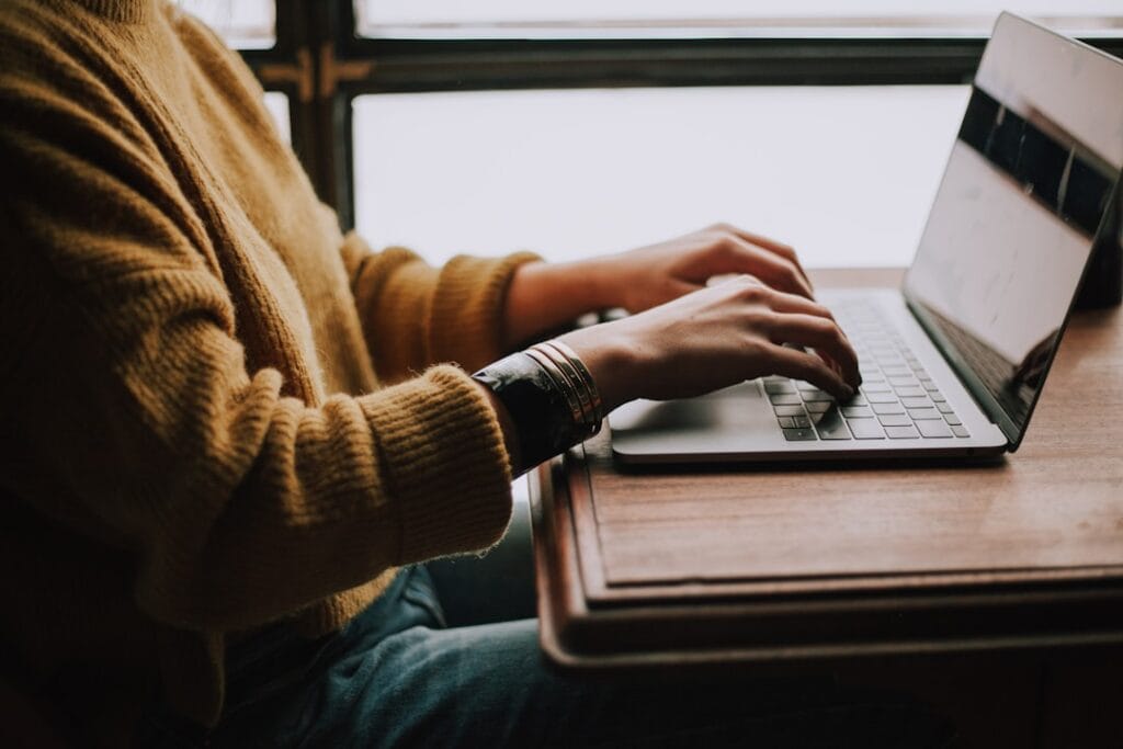 Google Docs Download: Every Export Format (2026) Person typing on a laptop to export and download a Google Doc on desktop