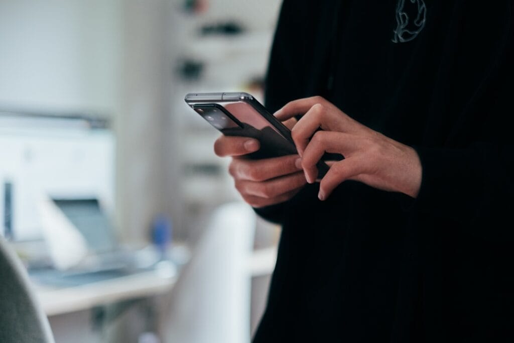 Google Docs Download: Every Export Format (2026) Person using a smartphone to access the Google Docs mobile app on iOS or Android