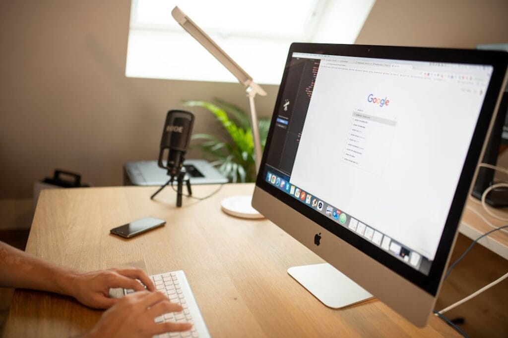 Google Drive Share Folder: Setup & Permissions Person typing on a desktop Mac with Google open in the browser, illustrating how to share a Google Drive folder from a desktop browser.