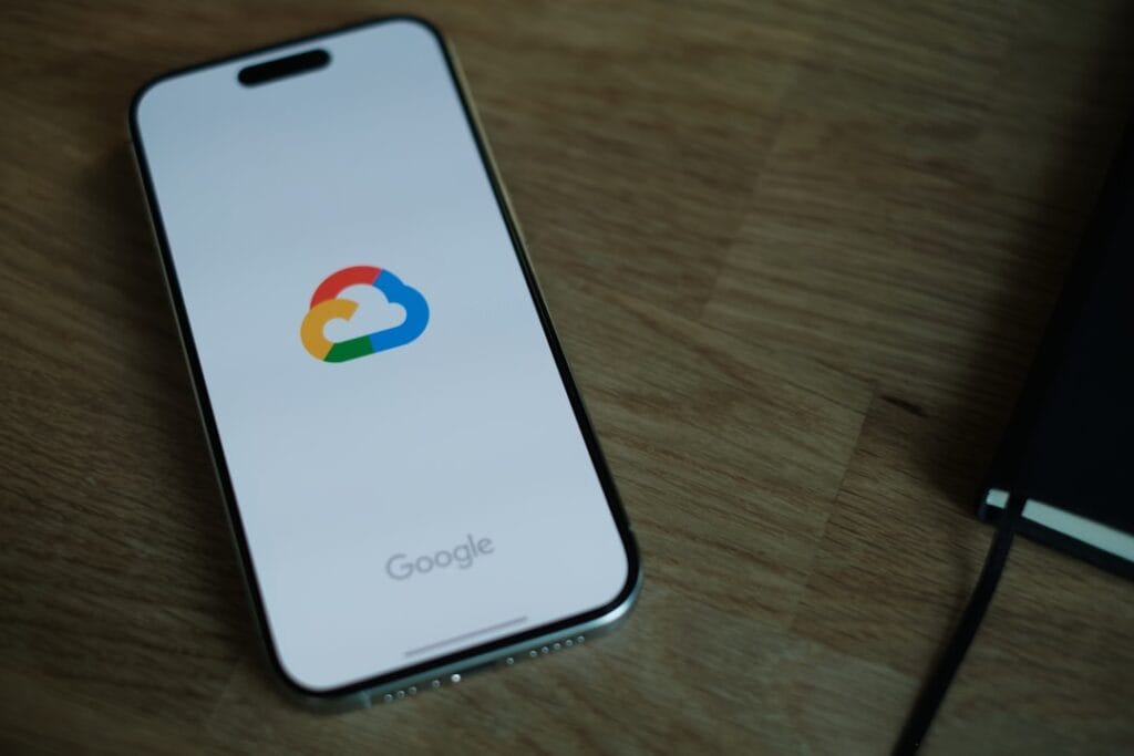 Gmail Storage Full? 5 Ways to Free Space Fast iPhone on a wooden table displaying the Google One cloud storage logo, representing Google Photos backup settings