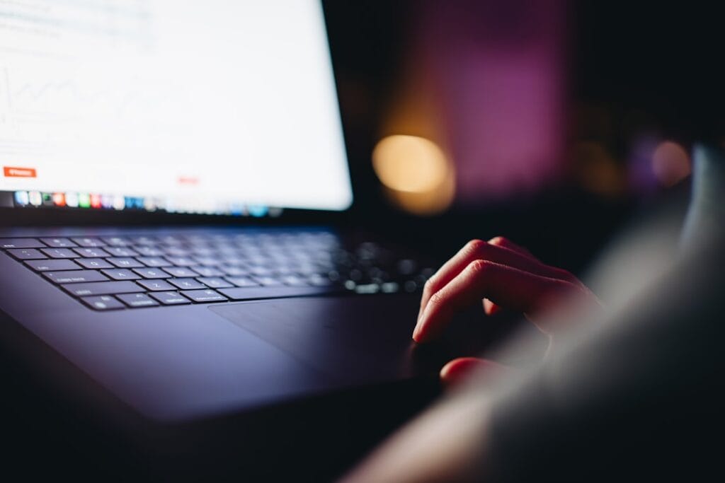 Person typing on a laptop in low light, using an online tool to download a file from Google Drive quickly.